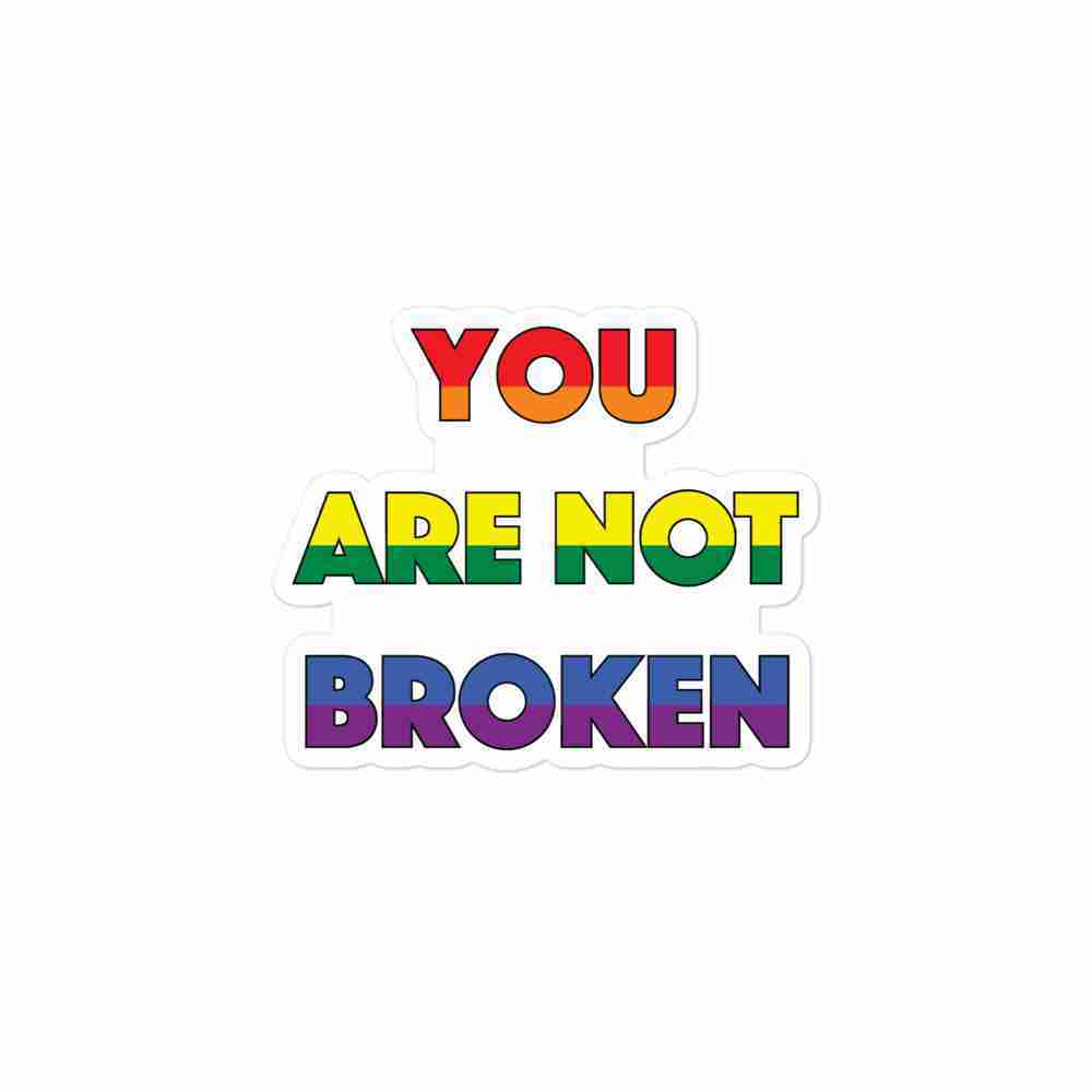 A sticker of text reading "You are not broken" in all caps; "You" is striped red and orange horizontally, "are" is striped yellow and green horizontally, and "broken" is striped blue and purple horizontally.